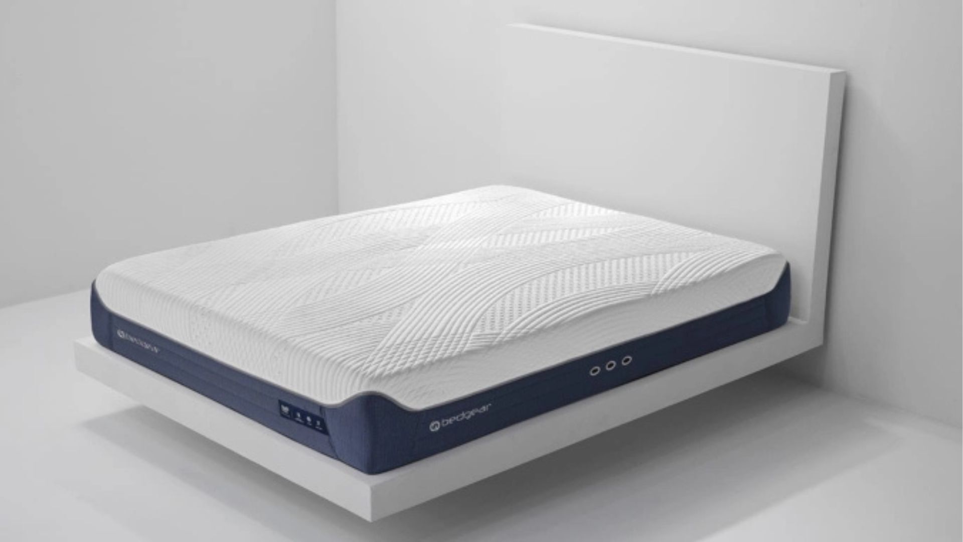 Modern ergonomic mattress on minimalist wooden frame against white wall for serene bedroom.