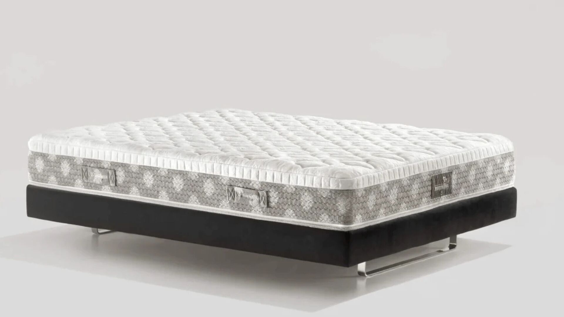 Tufted modern mattress on sleek black base with geometric sides for style and comfort.