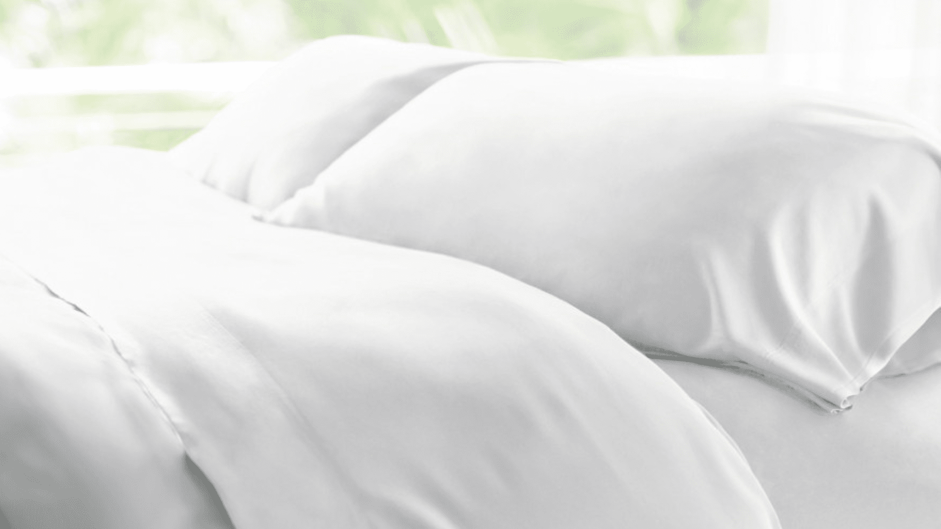 Luxurious white bedding with plush pillows in tranquil, natural light.