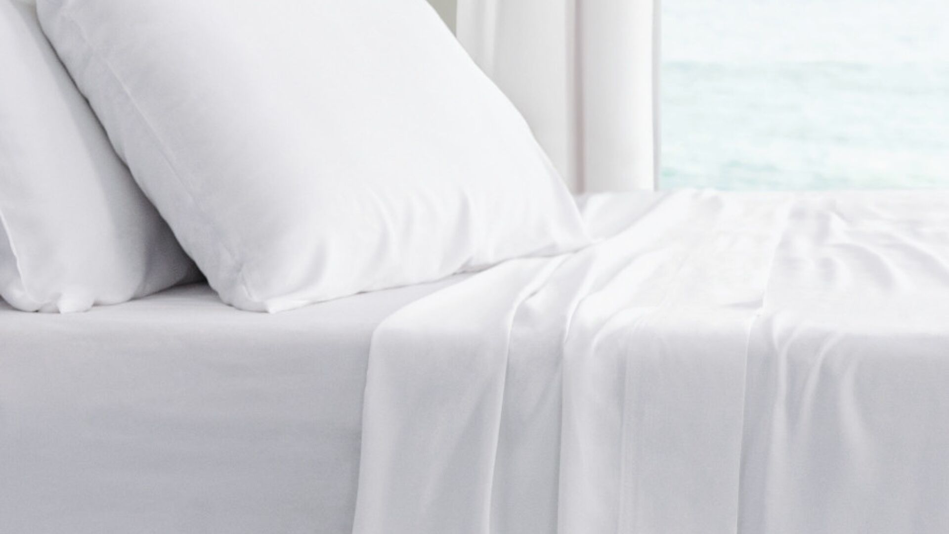 Serene bedroom with ocean view, white linens, inviting relaxation and peace.