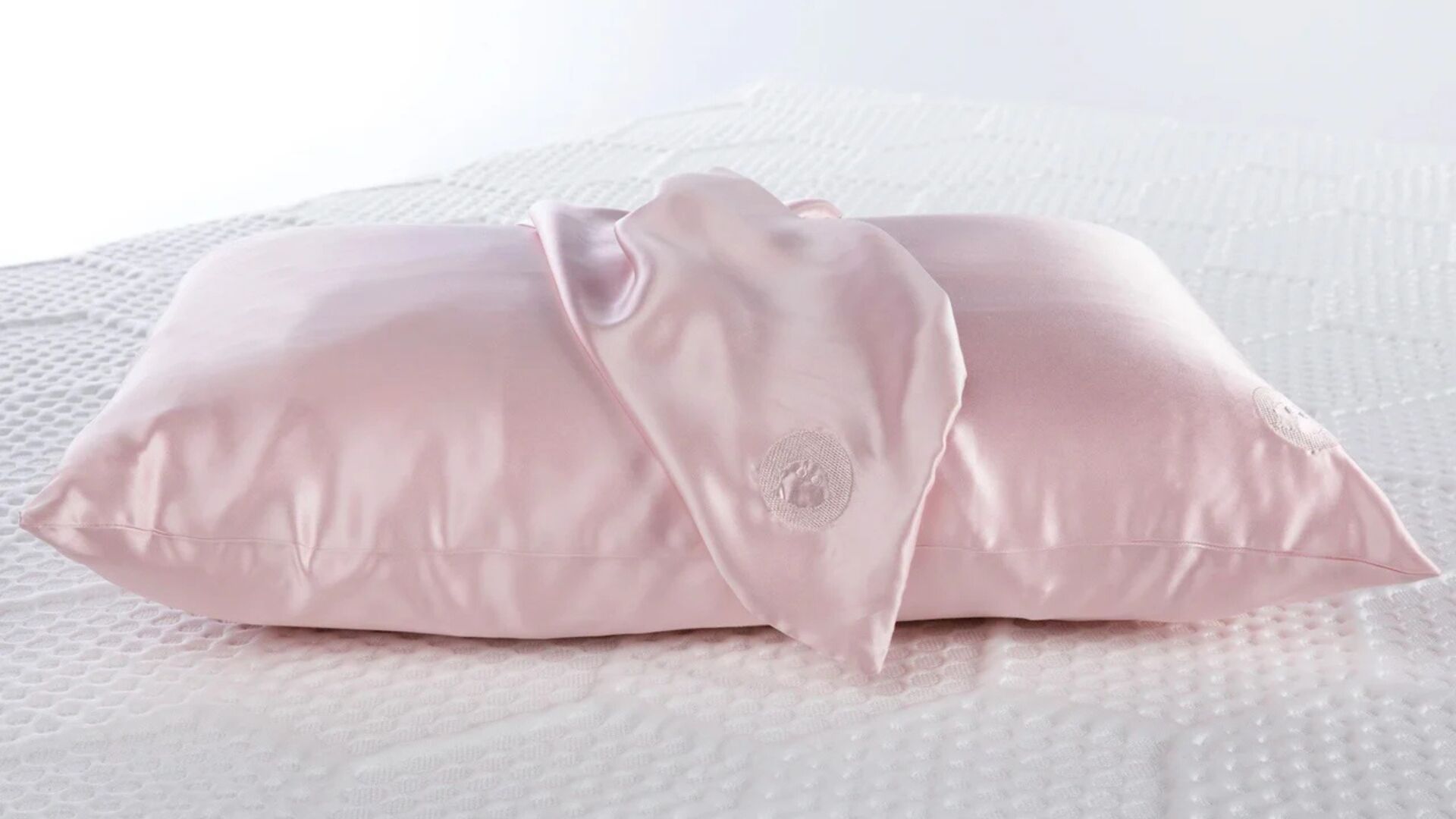 Luxurious satin pink pillow with elegant draped fabric, highlighting sophistication and comfort.