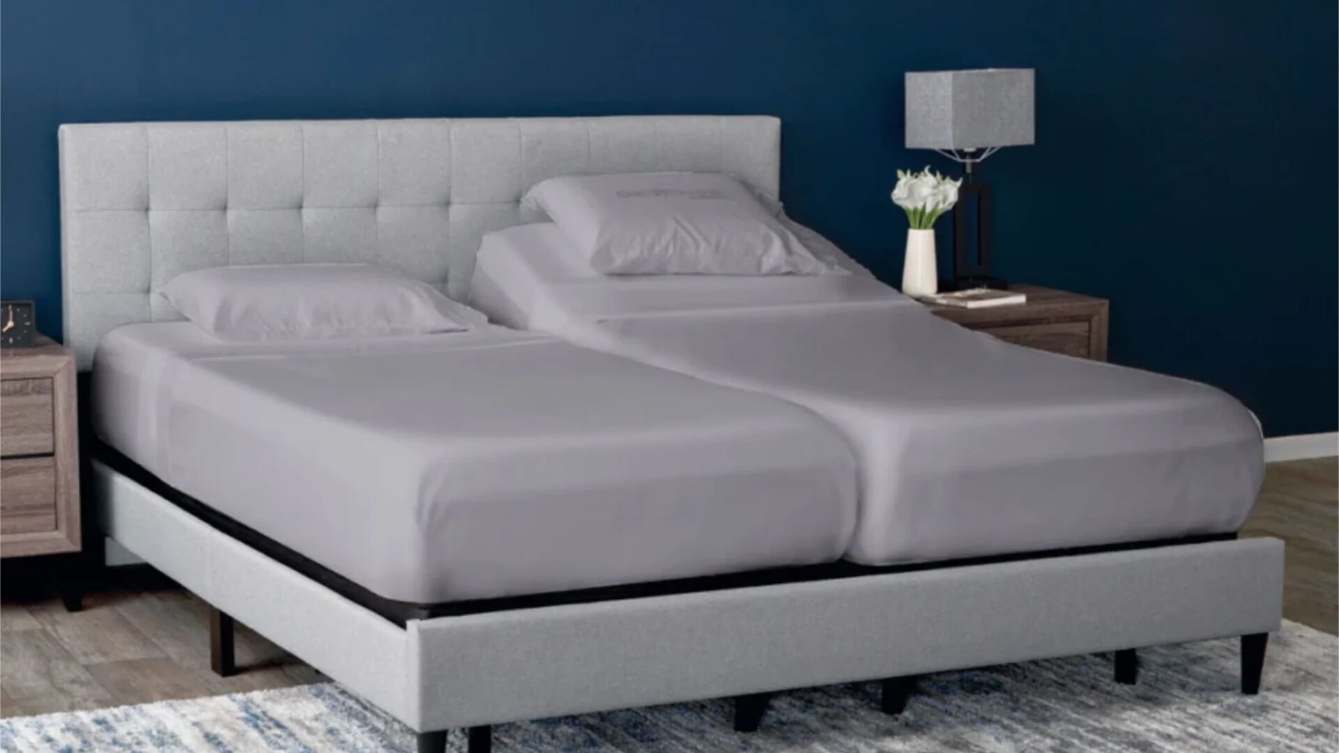 Modern bedroom with a split king bed, gray headboard, blue wall, and wooden nightstands.