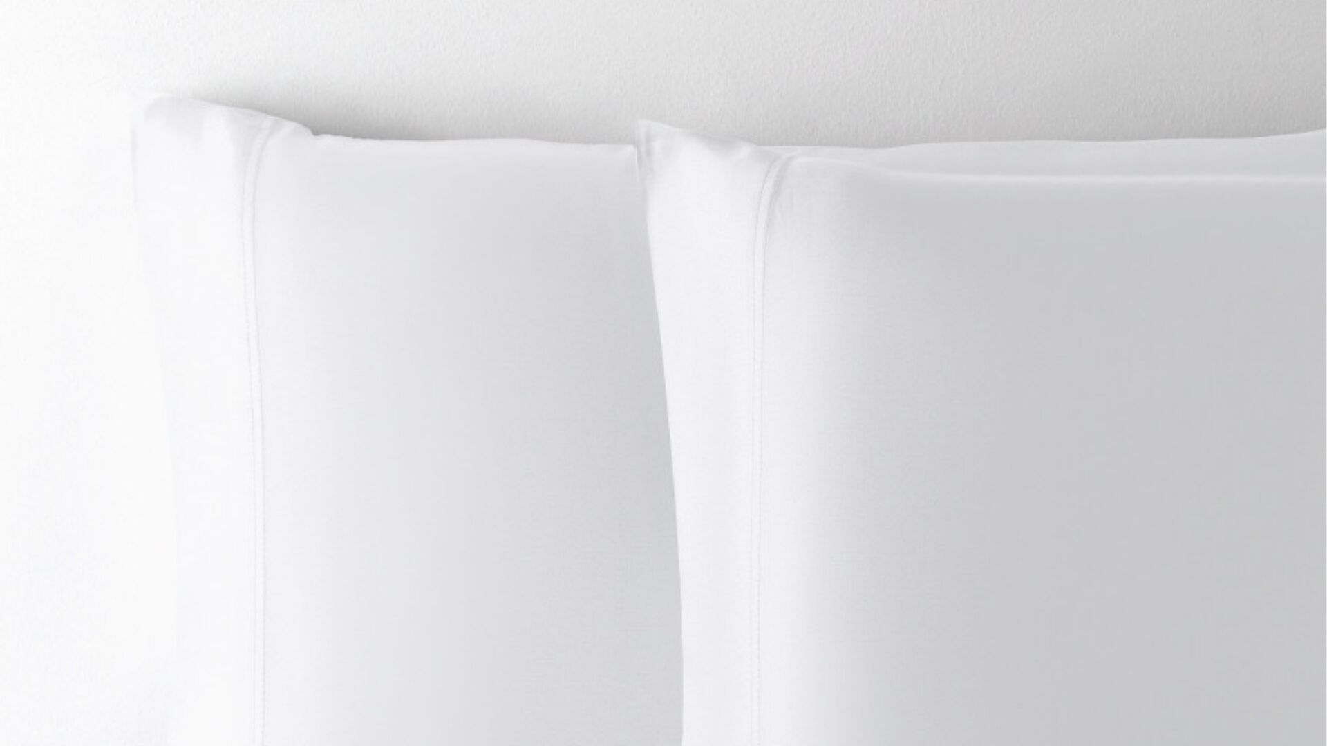 Luxurious white pillowcases with elegant piping for a tranquil and sophisticated bedroom ambiance.