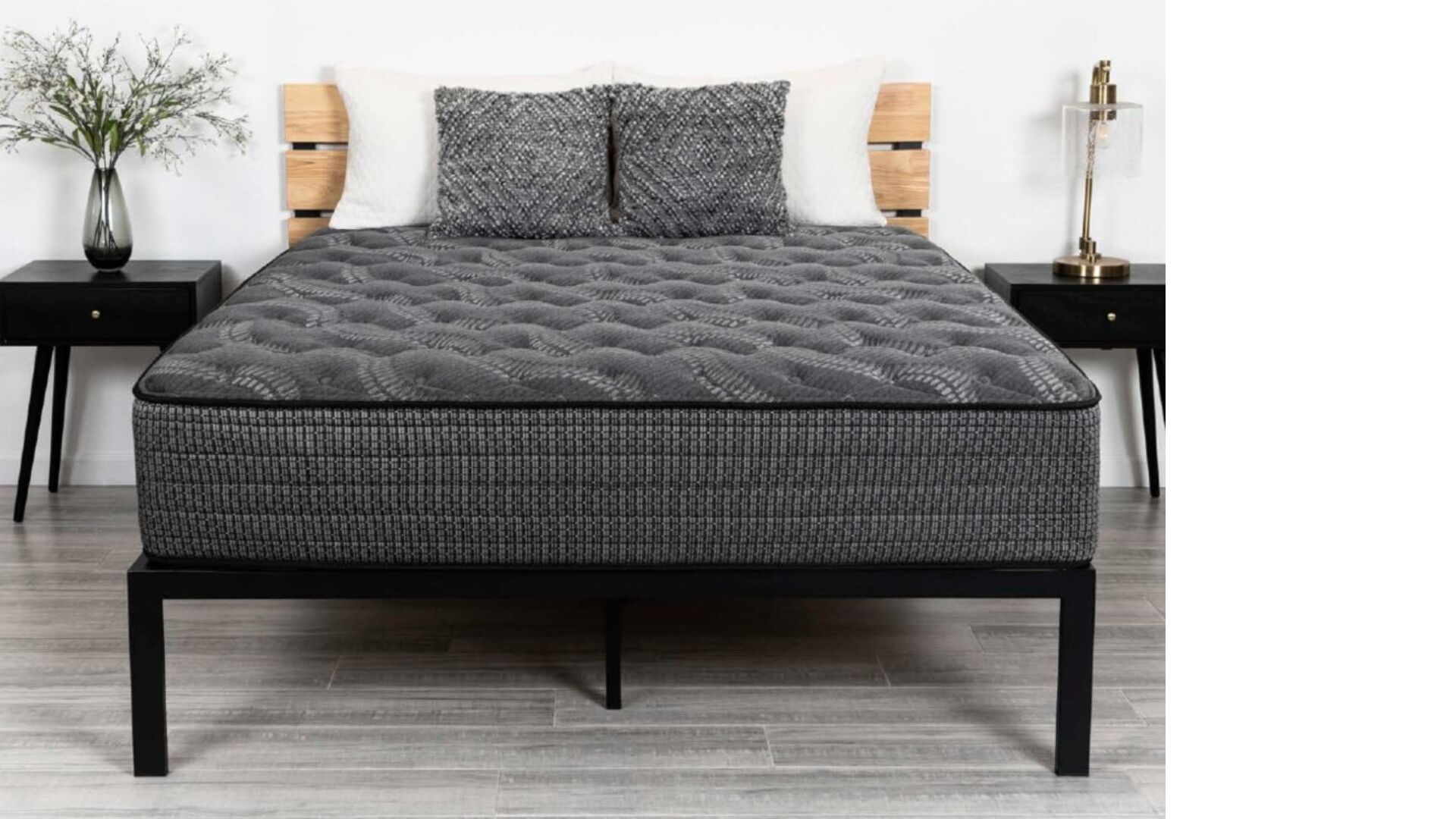 Modern bedroom with gray mattress, black frame, stylish pillows, and elegant nightstands.